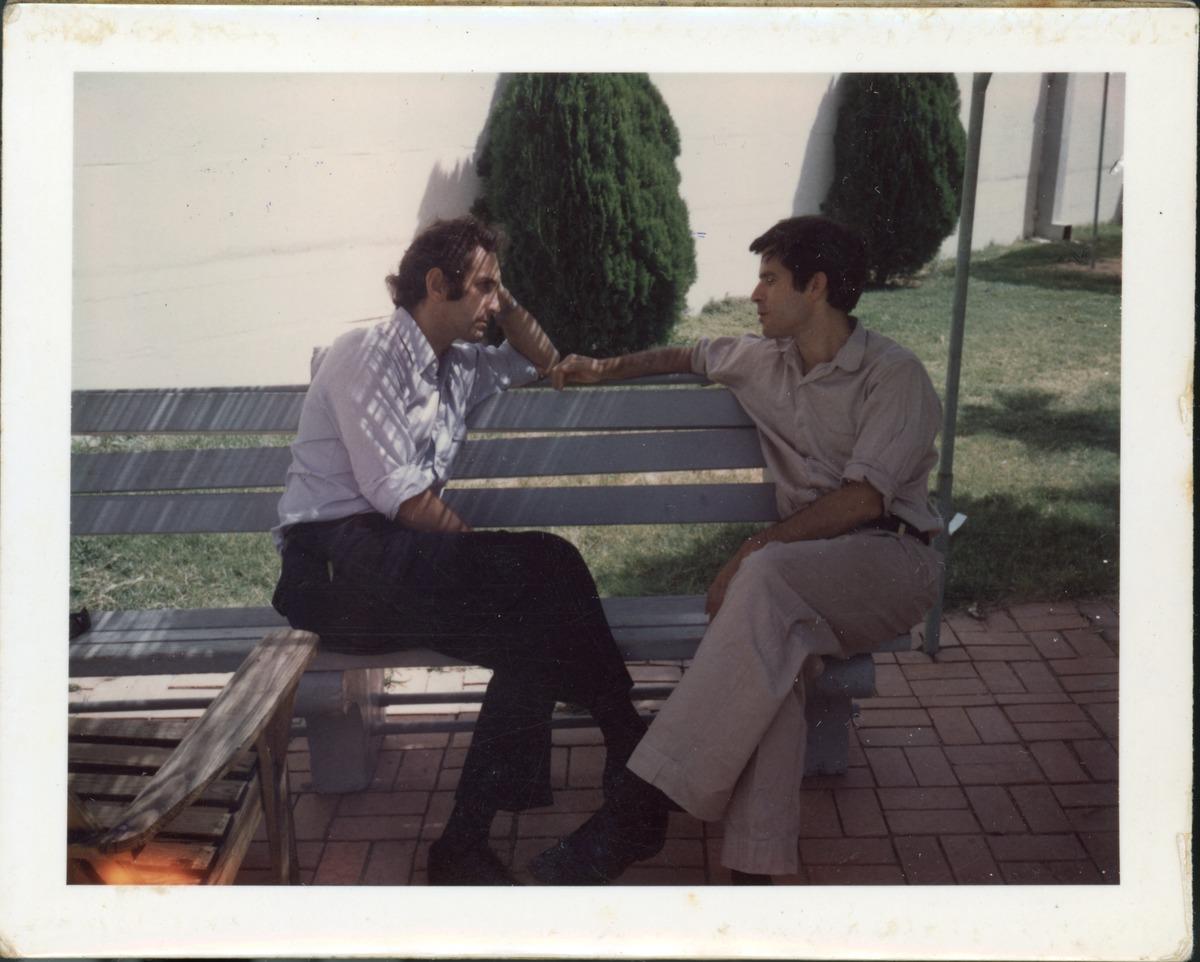 A couple of men sitting on a bench
Description automatically generated with low confidence