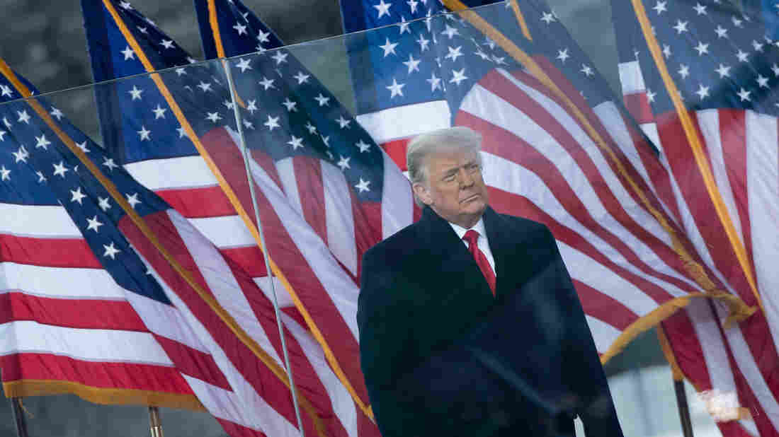 A person standing in front of several flags
Description automatically generated with medium confidence