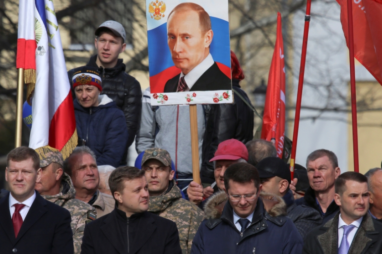 A man holds a portrait of Vladimir Putin during celebrations of the fifth anniversary of Russia's annexation of Crimea in Simferopol, Crimea March 15, 2019 [Alexey Pavlishak/Reuters]