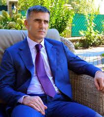 A person in a suit sitting on a bench

Description automatically generated with medium confidence