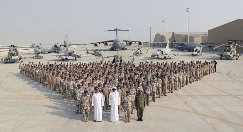 In this Monday, Sept. 11, 2017 photo released by Qatar News Agency, QNA, the Qatari Emir Sheikh Tamim bin Hamad Al Thani, centre front, poses for a photo with Emiri Air Force at al-Udeid Air Base in Doha, Qatar. Sheikh Tamim bin Hamad Al Thani's visit to al-Udeid Air Base throws into sharp relief the delicate balancing act the U.S. faces in addressing the Qatar crisis. (QNA via AP)