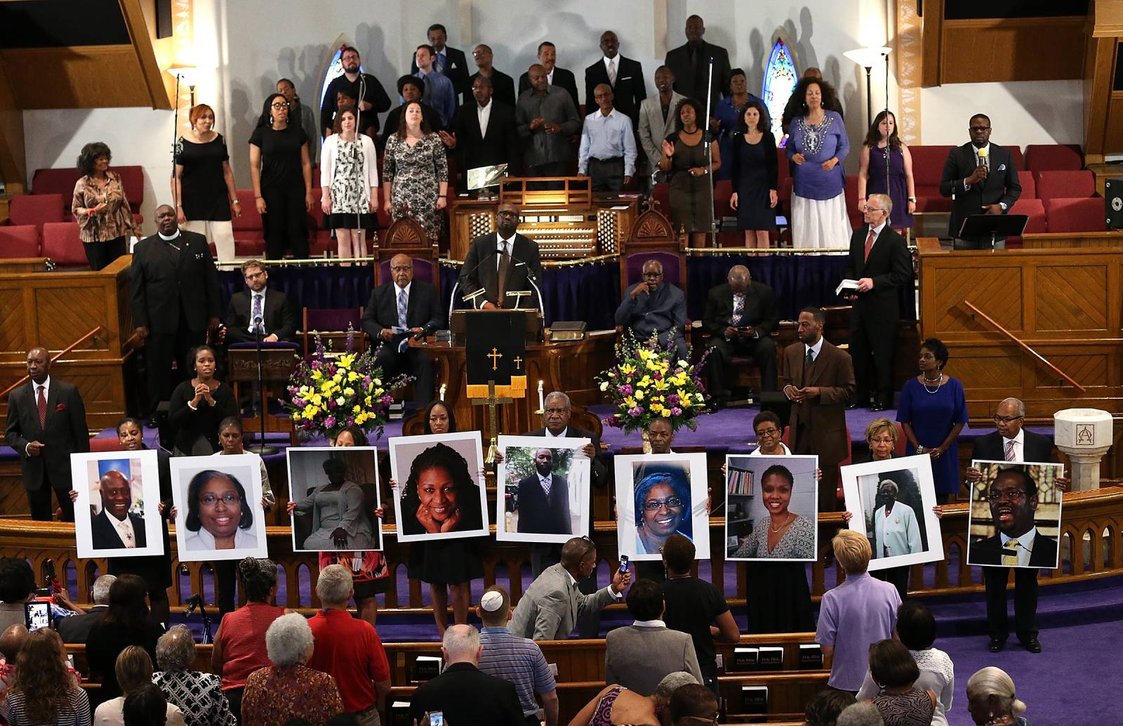 Photographs of the nine victims killed at the Emanuel African Methodist Episcopal Church in Charleston are held up by congregants during a prayer vigil at the the Metropolitan AME Church June 19, 2015 in Washington, DC.