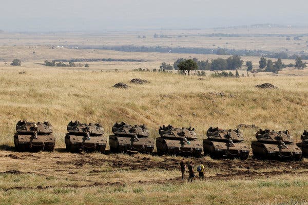 Israeli soldiers walking past tanks near the border with Syria in the Golan Heights.