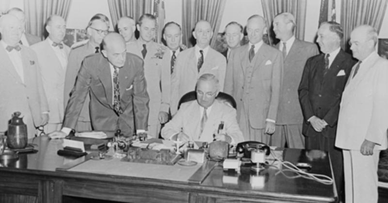 A group of men standing around a table

Description automatically generated with medium confidence