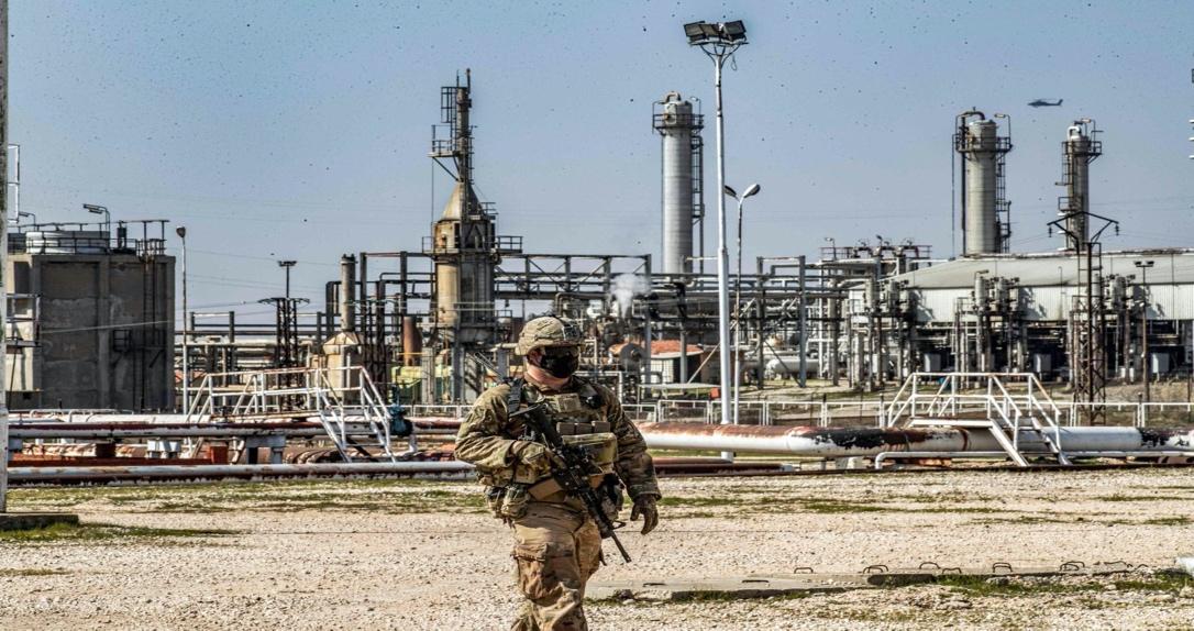 A United States soldier looks on while an AH-64 Apache assault helicopter flies above during a patrol by the Suwaydiyah oil fields in Hassakeh province, northeastern Syria, Feb. 13, 2021. (AFP File Photo)