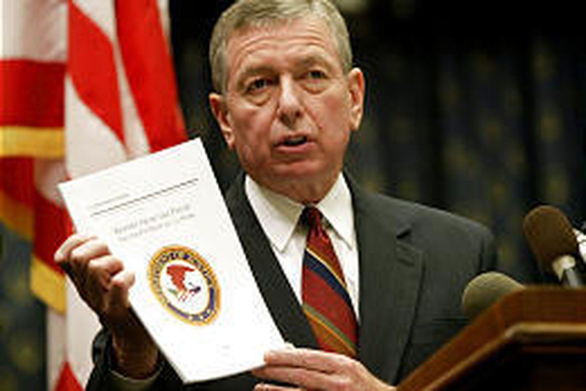 Attorney General John Ashcroft holds up a copy of "Report from the Field: The USA Patriot Act at Work" at a news conference Tuesday.