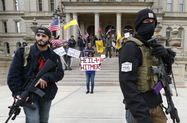 FILE - In this April 15, 2020 file photo, protesters carry rifles near the steps of the Michigan State Capitol building in Lansing, Mich. A plot to kidnap Michigan’s governor has put a focus on the security of governors who have faced protests and threats over their handling of the coronavirus pandemic. The threats have come from people who oppose business closures and restrictions on social gatherings. (AP Photo/Paul Sancya File)


