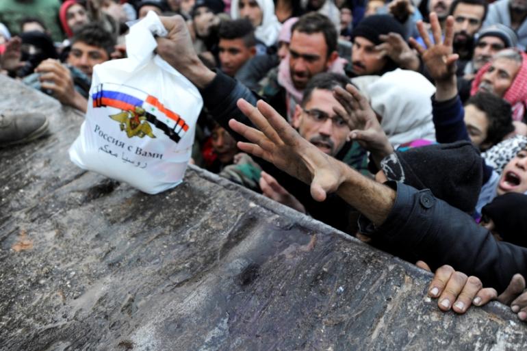 Syrians who fled east Aleppo reach for Russian aid in the government-controlled area of Jibreen [AP]