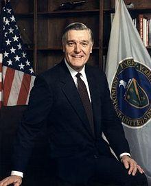 A person in a suit sitting in front of flags

Description automatically generated with medium confidence