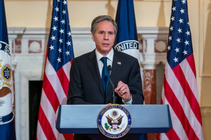 A person standing at a podium with microphones and flags behind him

Description automatically generated with medium confidence