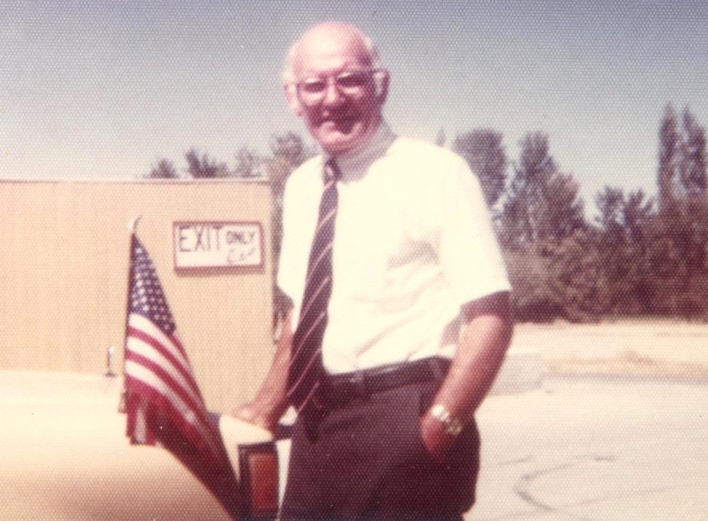 A person standing in front of a flag
Description automatically generated with medium confidence