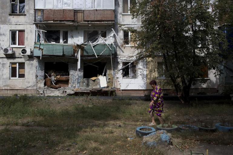 A person standing in front of a house that is falling apart

Description automatically generated with low confidence