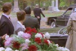 Funeral goers watching a mysterious man walk away from the funeral