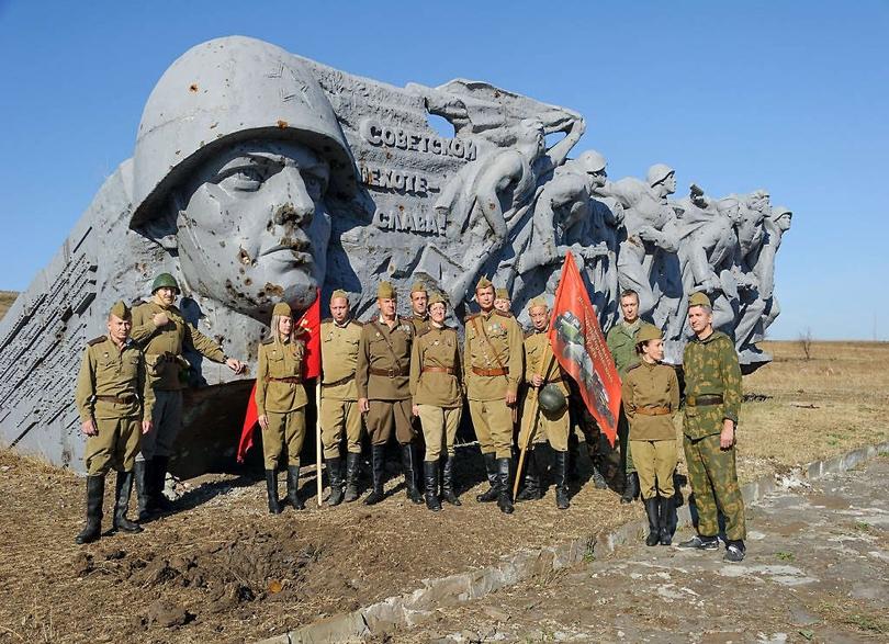 World War II reenactors pose in front of memorial