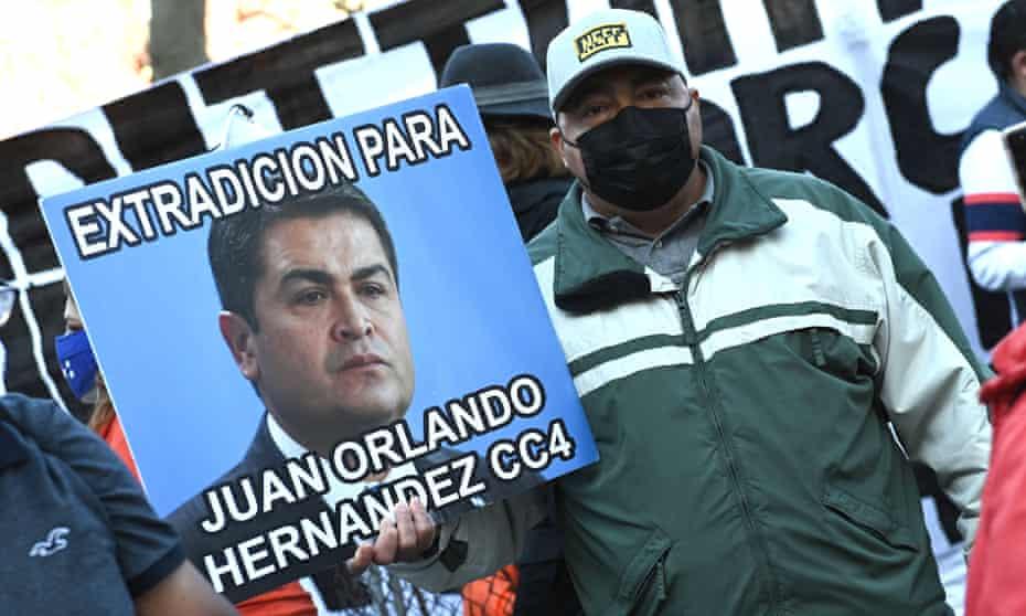 A protester holds a sign recommending that Honduran President Juan Orlando Hernández be extradited.