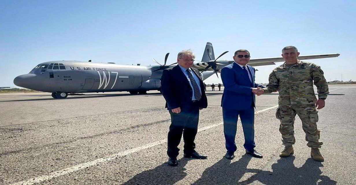 A group of men standing in front of a military plane

Description automatically generated with medium confidence
