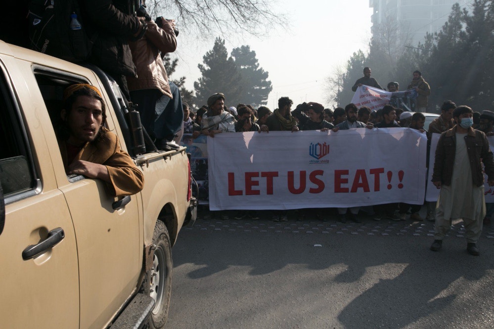 KABUL, AFGHANISTAN - DECEMBER 21: Afghans holding banners take part in a protest and march towards former US embassy building demanding the release of Afghanistan's frozen assets and resuming international funds amid worsening economic conditions and rising poverty in the country in Kabul, Afghanistan on December 21, 2021. Following Taliban's takeover, international funds to Afghanistan were halted, and the country's assets abroad were frozen. (Photo by Bilal Guler/Anadolu Agency via Getty Images)