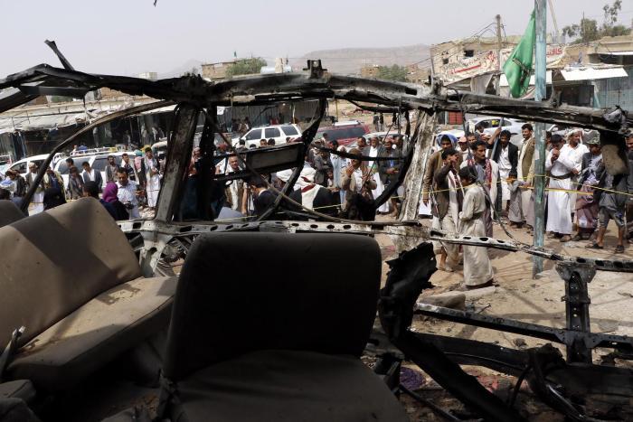 People are seen near a bus destroyed by an airstrike that killed dozens of children, in a photograph taken on August 12, 2018 in Saada, Yemen.
