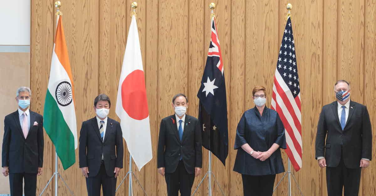 A group of men standing in front of flags
Description automatically generated with medium confidence