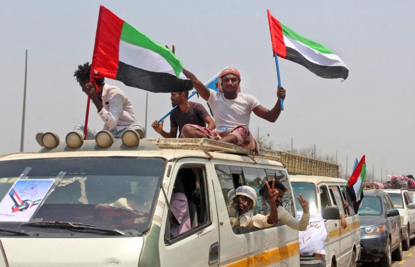 A group of people in a car holding flags

Description automatically generated with low confidence