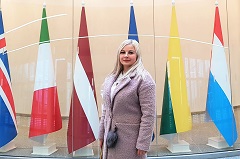 A person standing in front of flags

Description automatically generated with medium confidence