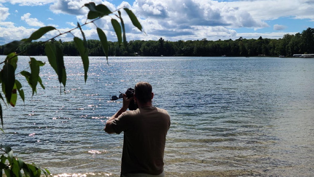 A person taking a picture of a lake

Description automatically generated with medium confidence
