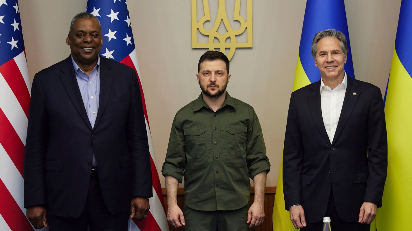 A group of men standing in front of flags
Description automatically generated