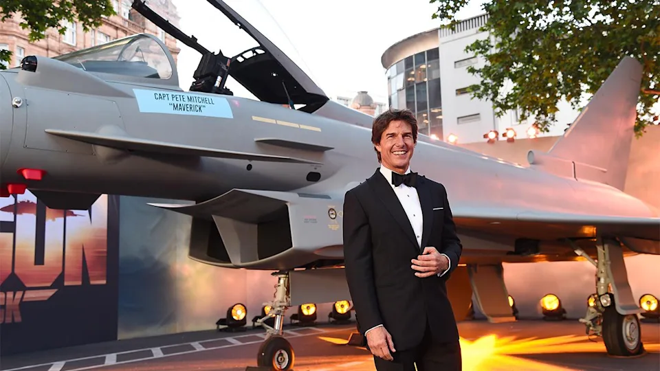 A person in a tuxedo standing next to a helicopter

Description automatically generated with medium confidence