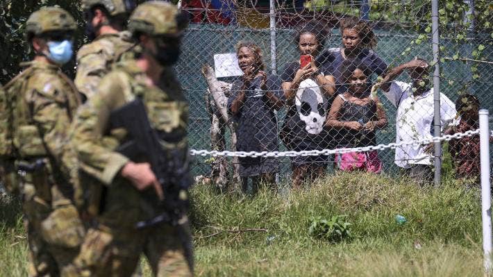 Locals photograph Australian soldiers and Australian Federal Police as they patrol the streets in Honiara, Solomon Islands.