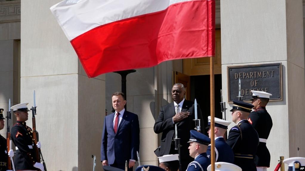 Defense Secretary Lloyd Austin, right, stands with Polish Defense Minister Mariusz Błaszczak, left, as the National Anthem is played during an arrival ceremony at the Pentagon in Washington, Apr. 20, 2022. 