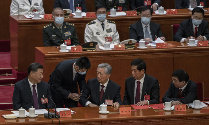 Chinese leader Xi Jinping (bottom left), Li Zhanshu, and Wang Huning (right), look on as former leader Hu Jintao (center) speaks to Xi as he is helped to leave early from the closing session of the 20th National Congress of the Chinese Communist Party at The Great Hall of People in Beijing, China, on Oct. 22, 2022. (Kevin Frayer/Getty Images)