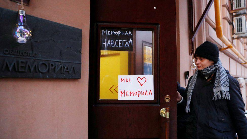 A man enters an office of the human rights group Memorial in Moscow, Russia. Placards read: "Memorial forever" (top) and "We love Memorial". Photo: December 2021