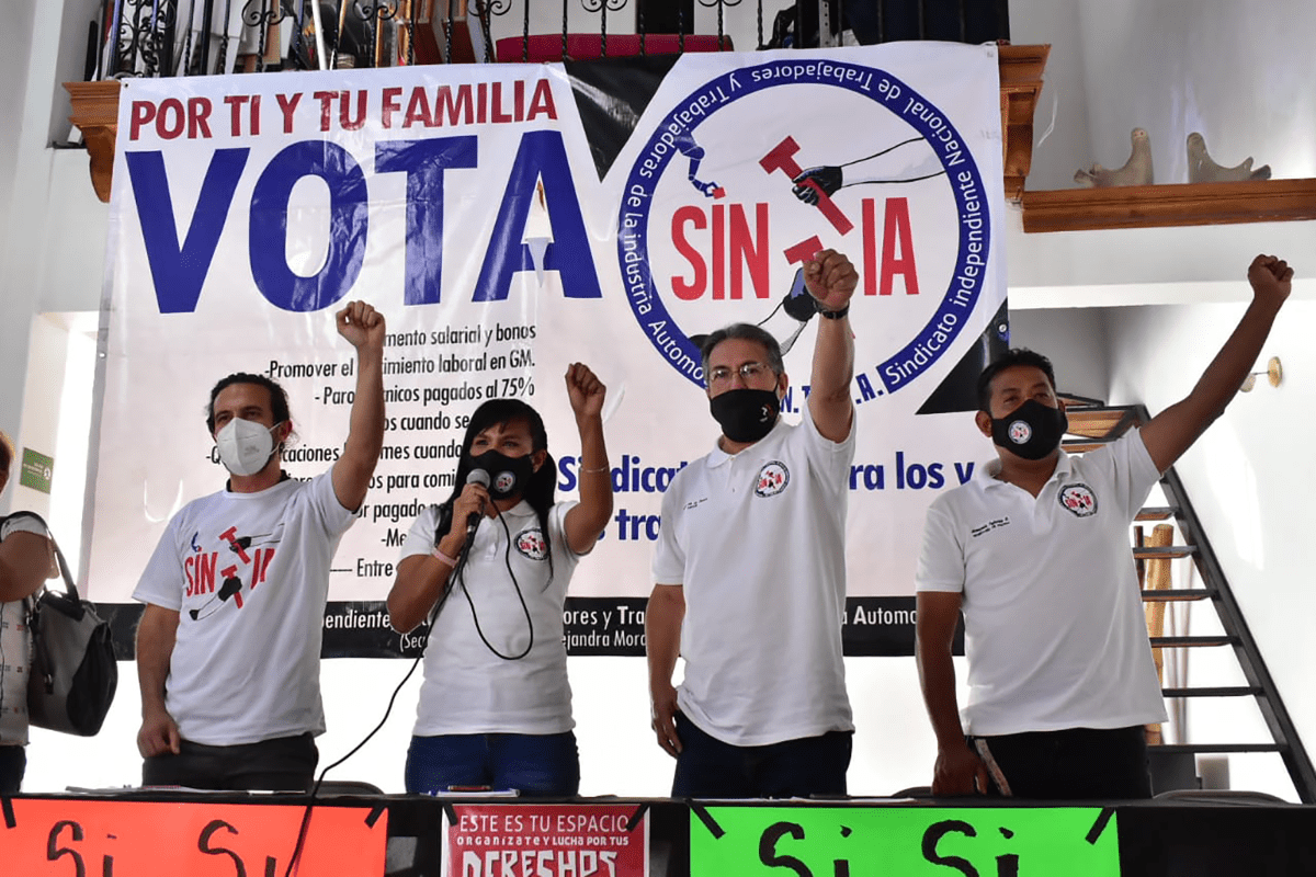 A group of people holding up a sign
Description automatically generated with low confidence