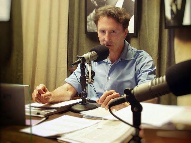 A person sitting at a desk with a microphone and papers

Description automatically generated with low confidence