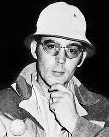 Portrait photograph of a 33-year-old man wearing a denim jacket, a bucket hat, and sunglasses