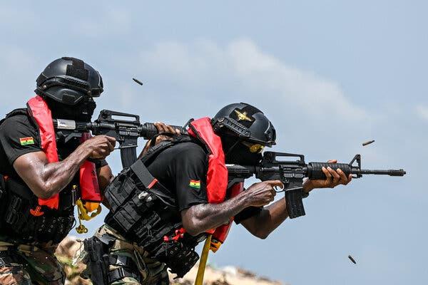 Two Ghanaian soldiers firing machine guns.
