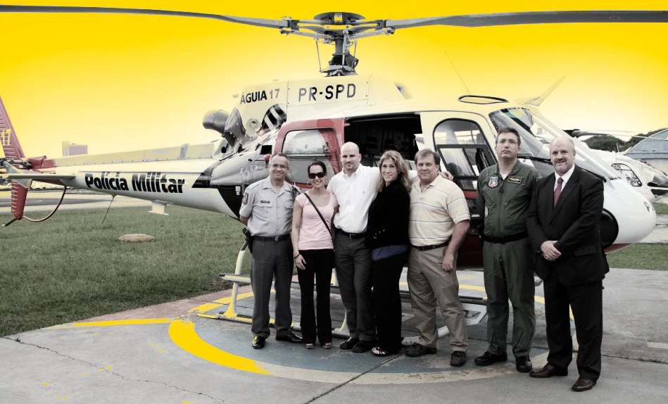 A group of people standing in front of a helicopter

Description automatically generated
