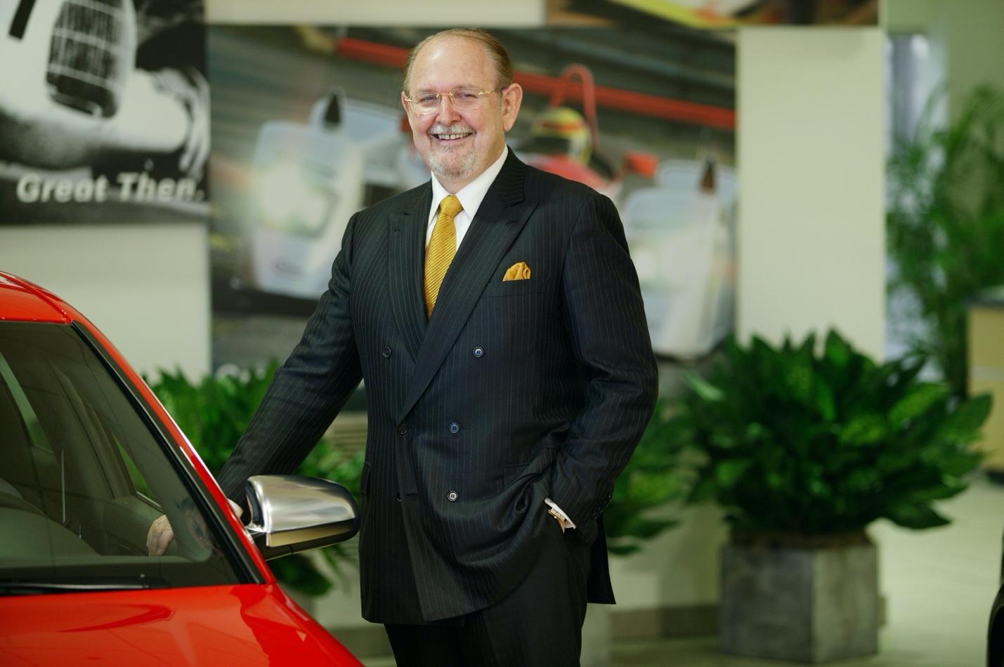 A person in a suit standing next to a car

Description automatically generated with low confidence