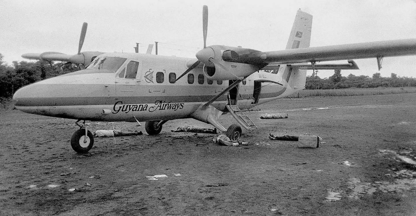 The bodies of San Francisco Examiner photographer Greg Robinson, center under engine, and Rep. Leo Ryan, on the opposite side of the plane under the word "Guyana," lie on the ground beside an airplane at the Port Kaituma airstrip.