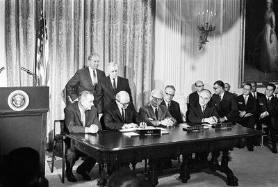 A group of men signing papers at a table
Description automatically generated