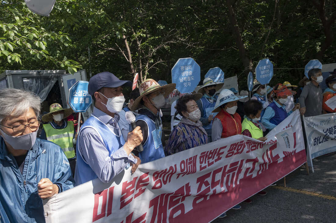 A group of people holding signs and a banner

Description automatically generated
