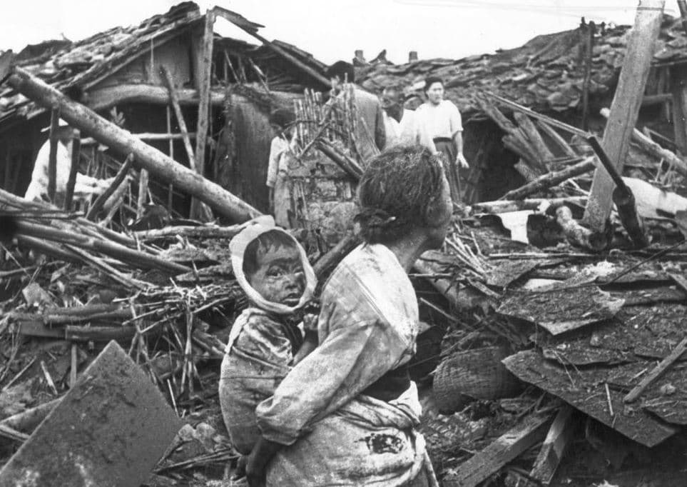 A person carrying a child in a destroyed house

Description automatically generated