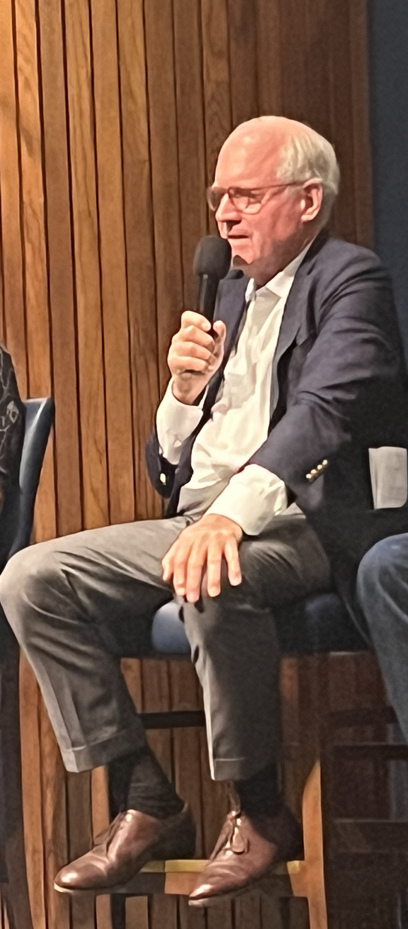 A person sitting in a chair holding a microphone
Description automatically generated