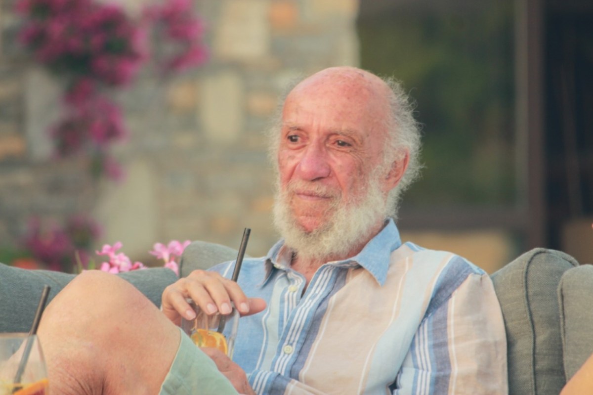 An old person sitting in a chair drinking a drink
Description automatically generated