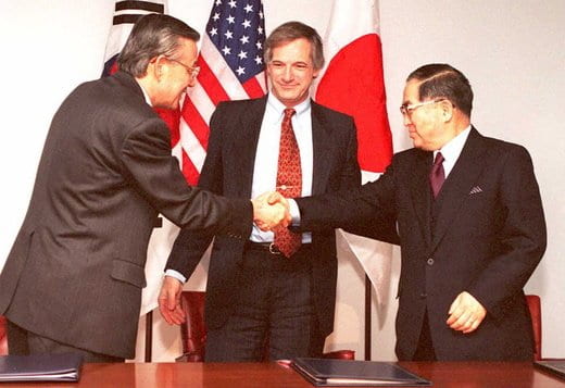 Men shaking hands in front of flags

Description automatically generated