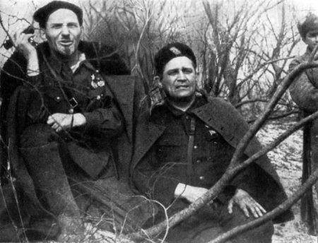 A couple of men sitting in the woods

Description automatically generated
