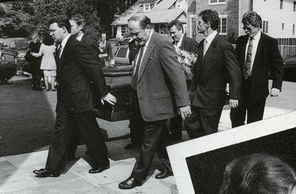 A group of men walking down a sidewalk

Description automatically generated