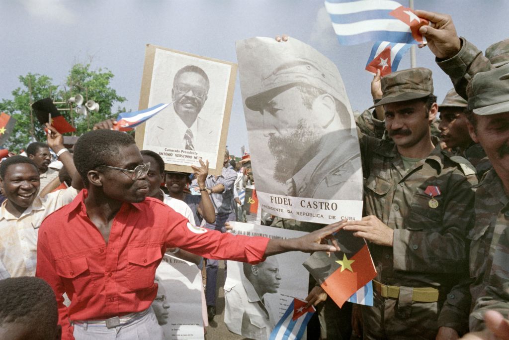 A group of people holding pictures of cuban soldiers

Description automatically generated