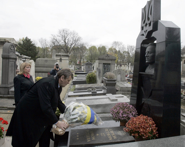 A person and person placing flowers on a grave

Description automatically generated