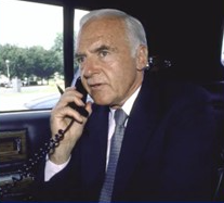 A person in a suit talking on a phone

Description automatically generated
